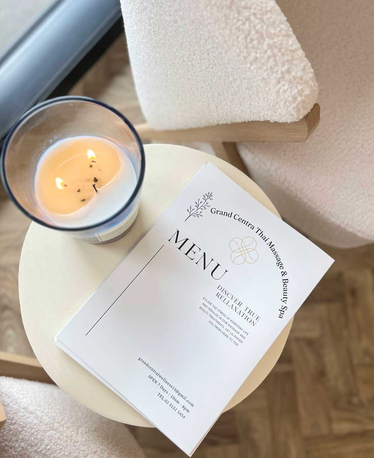 Grand Central Thai Massage & Beauty Spa menu beside a candle and folded towels